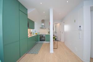 kuchnia z zielonymi szafkami i białą ścianą w obiekcie Central & Stylish 2 Bedroom Apartment w/ Balcony w mieście Cascais