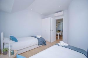 two beds in a white room with a table at Central & Stylish 2 Bedroom Apartment w/ Balcony in Cascais