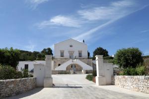 a white house with a gate and a stone wall at Donna Silvia Apartments in Castellana Grotte