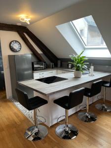 une cuisine avec un îlot doté de chaises et d'une horloge dans l'établissement Coeur de bouchon, à Troyes