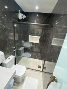 uma casa de banho com um WC e uma cabina de duche em vidro. em Pousada Amaral Búzios em Búzios
