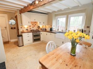 a kitchen with a wooden table with yellow flowers on it at Cherry Tree Cottage in Bingley