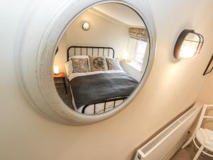 a mirror in a bedroom with a bed in it at Cherry Tree Cottage in Bingley