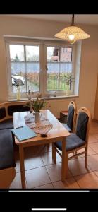 a living room with a table and chairs and two windows at Ferienwohnung Margrit in Detern