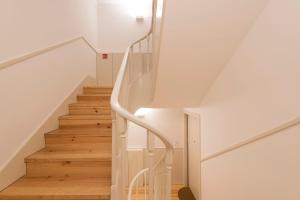 eine weiße Treppe in einem Haus mit Holzböden in der Unterkunft Tripas Coração Taipas Historical Center in Porto