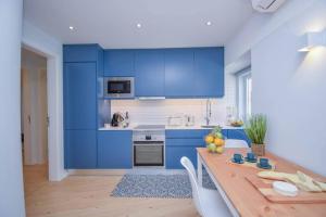 a kitchen with blue cabinets and a wooden table at Charming Seaside Apartment - 1 min from the beach in Cascais