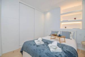 a white bedroom with a bed with towels on it at Charming Seaside Apartment - 1 min from the beach in Cascais