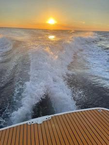 a boat in the ocean with the sunset in the background at Appartamento shamal in Marina di Cecina