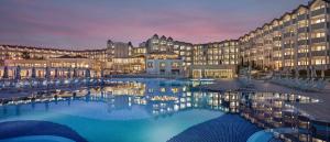 シダにあるArcanus Hotels Sorgun - Ultra All Inclusiveの大きな建物の正面に大きなプールがあります。