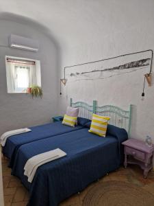 a bedroom with a blue bed with yellow and pink pillows at PENSION SOCAIRE CONIL in Conil de la Frontera