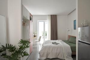 a white bedroom with a bed and a green couch at M Village Cao Thắng 2 in Ho Chi Minh City