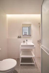 La salle de bains est pourvue d'un lavabo blanc et de toilettes. dans l'établissement M Village Cao Thắng 2, à Hô-Chi-Minh-Ville