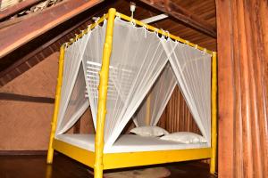 ein gelbes Bett mit weißen Netzen in einem Zimmer in der Unterkunft LOCAVACATION Les Hauts Manguiers Villa 2 in Nosy Be