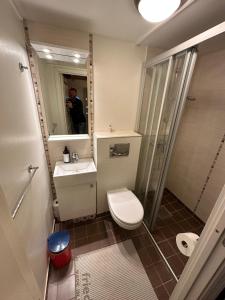 a man taking a picture of a bathroom with a toilet and sink at Handkleppveien 26 - Fishermans cabin in Straume