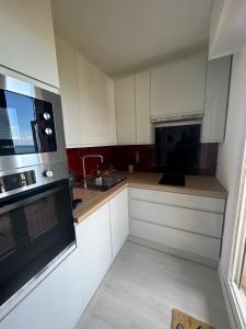 a kitchen with white cabinets and a sink and a microwave at Les Marines - Belle Vue Mer in Cabourg