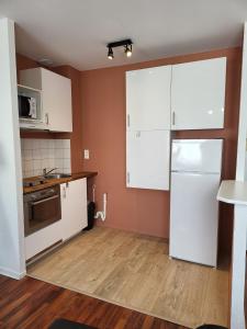 a kitchen with white cabinets and a white refrigerator at le T2 d'henri in Agen