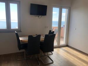 a dining room with a table and chairs and windows at Apartmani Ivana in Cres