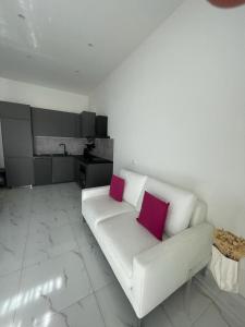 a living room with a white couch with two pink pillows at Casa Ariane in Ventimiglia