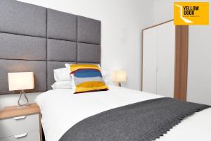 - une chambre avec un grand lit et un oreiller jaune dans l'établissement Baxter Park - City Base, à Dundee