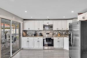 a kitchen with white cabinets and a stainless steel refrigerator at Modern Villa with Pool Hollywood Hard Rock Casino in Fort Lauderdale