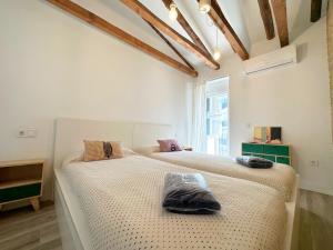 two beds in a white room with a window at Dos Torres Rivendel - Vistas a la Basílica del Pilar in Zaragoza