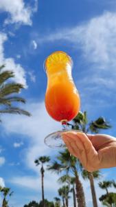 une main de personne tenant un verre de jus d'orange dans l'établissement TUI BLUE Falesia - Adults Only, à Olhos de Água