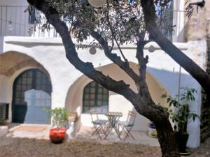 un árbol frente a un edificio con mesa y sillas en La Cachette, en Aigues-Vives