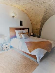 1 dormitorio con 1 cama grande y pared de piedra en La Cachette, en Aigues-Vives