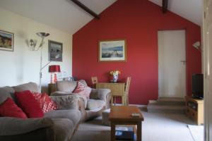 a living room with red walls and couches at Birslack Grange in Kendal