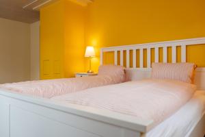 two beds in a room with yellow walls at Schlafen zur Brauerei St. Johann in Nesslau