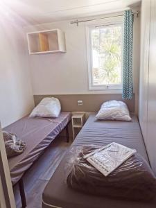 2 camas en una habitación pequeña con ventana en Mobil home Premium Camping 5* en Vendays-Montalivet