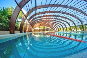 une piscine intérieure avec un tunnel au-dessus de l'eau dans l'établissement Mobil home Premium Camping 5*, à Vendays-Montalivet