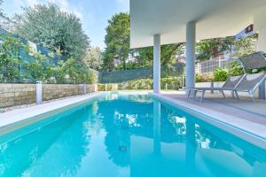 a swimming pool with two chairs next to a house at ApartmentsGarda - Le Terrazze Del Garda Residence in Lazise