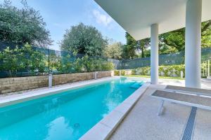 a swimming pool with a bench in front of a house at ApartmentsGarda - Le Terrazze Del Garda Residence in Lazise