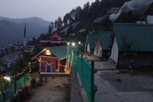 a house decorated with christmas lights on a mountain at Wild Himalaya Glamping Camp in Nārkanda