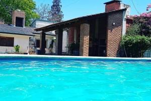 ein Haus und ein Pool mit blauem Wasser in der Unterkunft Casa con quincho y pileta in Cordoba + 18 Fotos