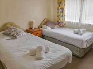 two beds in a bedroom with towels on them at Apartment 1 Waterrs Edge in Crantock