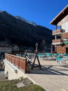 ein Gebäude mit einer Holzterrasse mit Tischen und Stühlen in der Unterkunft Large premium alpine apartment for 4 to 8 people in Vallorcine