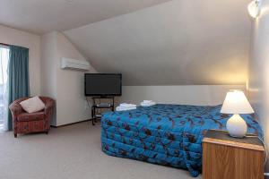 Habitación de hotel con cama y TV en Garden City Motel, en Christchurch