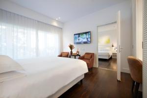 a hotel room with a large white bed and a tv at Magna Pars l'Hotel à Parfum in Milan