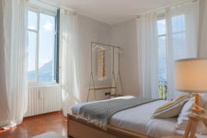una camera bianca con un letto e ampie finestre di Como Lake Vista - by MyHomeInComo a Blevio
