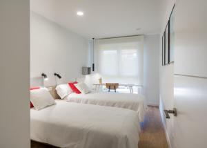 two beds in a white room with a table at BILBAO COSTA-Algorta-Getxo- A ESTRENAR-parking-playa-metro-BILBAO en metro, a 25 mimutos in Getxo