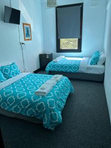 2 camas en un dormitorio con paredes azules y ventana en Historic Pub Accommodation- En-suites - Shared Bathroom Double Rooms - Shared Bathroom Twins, en Portland