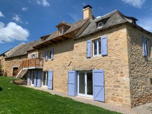La Combe aux Fées في Saint-Côme-dʼOlt: منزل حجري قديم بأبواب ونوافذ زرقاء