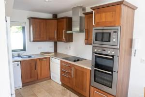 a kitchen with wooden cabinets and a microwave at Osher Apartment in Enniscorthy