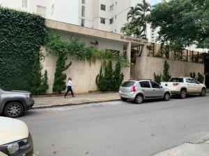 een vrouw die door een straat loopt met geparkeerde auto's bij Apartamento no Setor Bueno - imóvel completo e com excelente localização in Goiânia