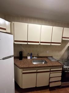 a kitchen with a sink and a white refrigerator at Apartamento no Setor Bueno - imóvel completo e com excelente localização in Goiânia