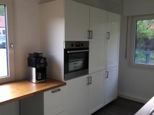 a kitchen with white cabinets and a microwave at Ferienhaus Bibernest in Münsingen