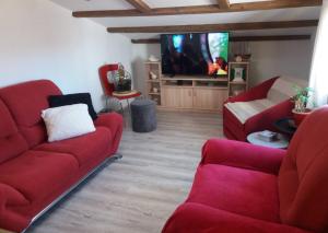 a living room with two red couches and a tv at Apartman Lea in Brodarica
