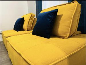 Un sofá amarillo con dos almohadas azules. en Fantastique 3 chambres modernes au cœur de la ville en Montreal